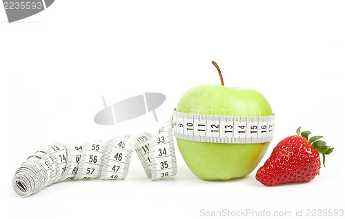 Image of Measuring tape wrapped around a green apple and strawberry as a symbol of diet