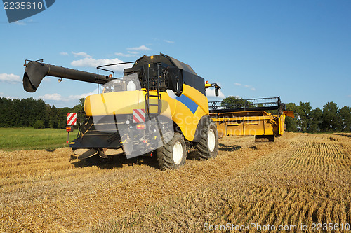 Image of Yellow harvester combine on field harvesting gold wheat