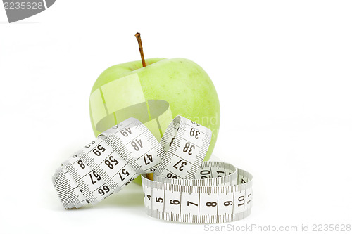 Image of Measuring tape and green apples as a symbol of diet