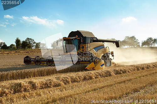 Image of Yellow harvester combine on field harvesting gold wheat