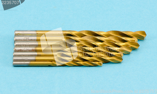 Image of different size golden color drill bits on blue 