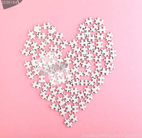 Image of Puzzle made heart shape on pink background 