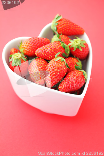 Image of Strawberry in heart shape bowl on red background