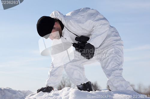 Image of Wounded soldier in white camouflage sneaking through the mountai