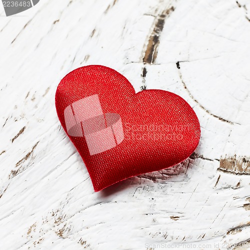 Image of single red heart on white wood background