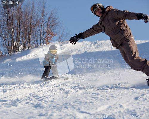 Image of Man snowboarder and little skier