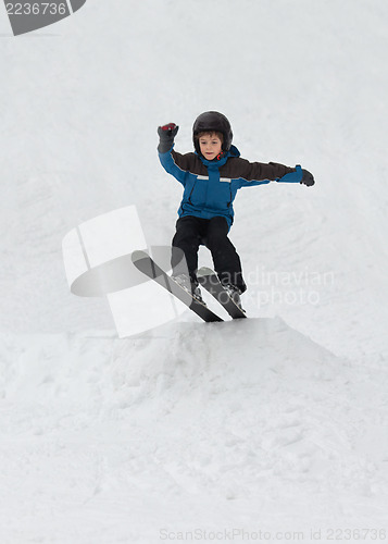 Image of Little boy jumping on snow skis