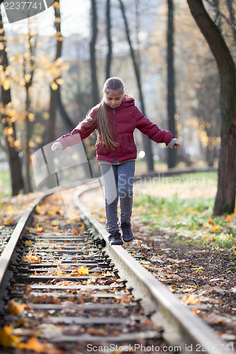 Image of Girl walking down train tracks