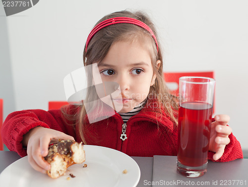 Image of Little girl eating donut with juice