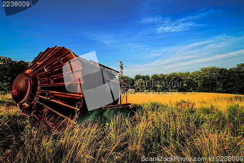 Image of old rusty rustic tower on its side in agricultural field