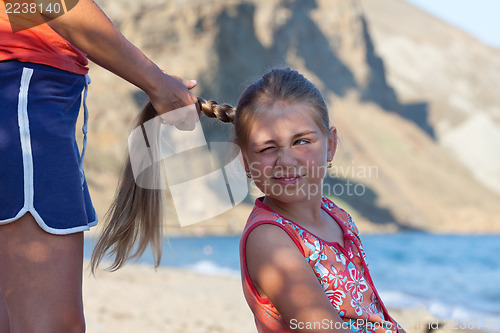 Image of Mother braiding daughter's hair outdoors