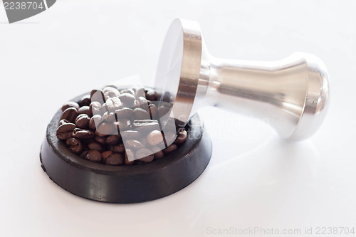 Image of Coffee tamper and roasted coffee in rubber saucer