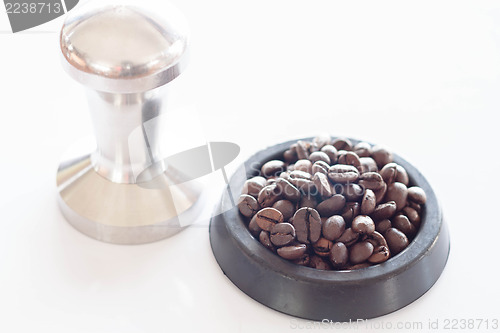 Image of Roasted coffee in rubber saucer and tamper 