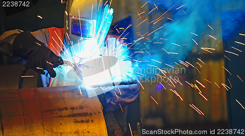 Image of worker with protective mask welding metal 