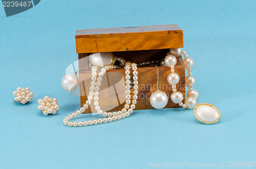Image of pearl jewelry retro wooden box on blue background 