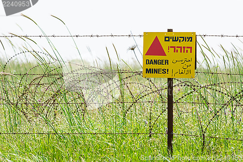 Image of Razor wire guard fence and warning sign on mines field