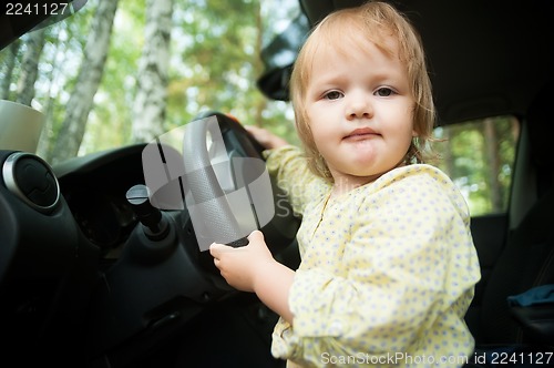 Image of Little blond girl driving car