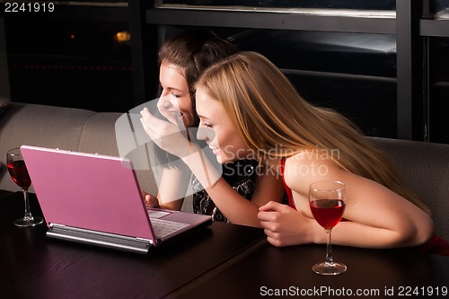 Image of Two beautiful women with laptop in cafe