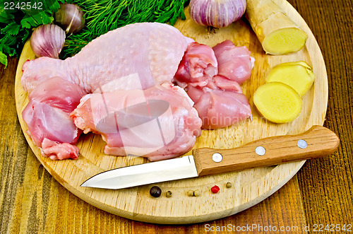 Image of Chicken leg cut on a wooden board with a knife