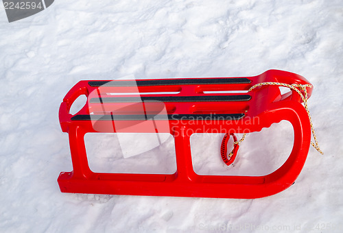 Image of plastic red sleigh with black rim yard in winter  