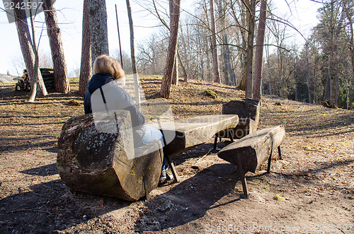 Image of blond woman sit wooden chair warm spring sun park 