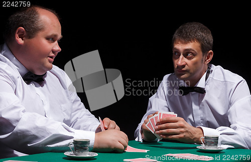 Image of Two gentlemen in white shirts, playing cards