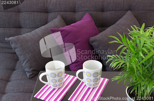 Image of Sofa with cushions and two cups on a table