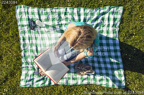Image of Young Woman Reading Book In Park, seen from above