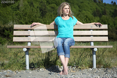 Image of Young Woman Sitting On Bench At Beach