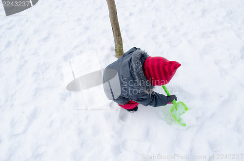 Image of girl with red hat shovel dig snow 