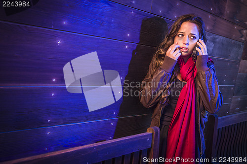 Image of Frightened Young Woman in Dark Walkway Using Cell Phone