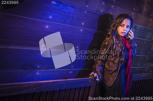 Image of Frightened Young Woman in Dark Walkway Using Cell Phone