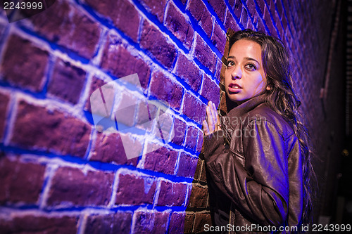 Image of Frightened Pretty Young Woman Against Brick Wall at Night