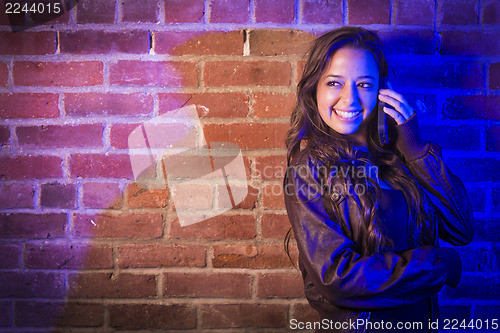 Image of Mixed Race Woman Using Her Cell Phone Against Brick Wall