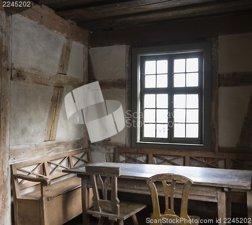 Image of rustic chamber with bench, table and chair.