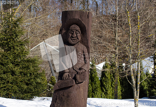 Image of rural wooden carved man statue snow winter park 