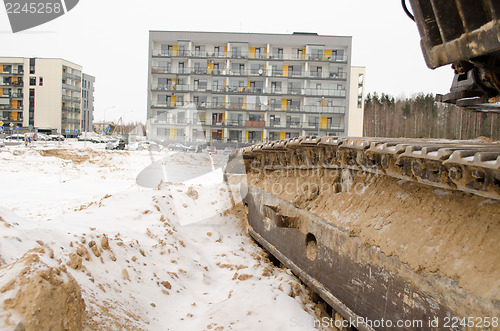 Image of heavy machinery caterpillar  cars houses snow 