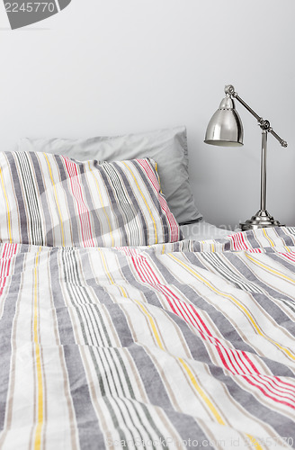 Image of Metal lamp near bed with colorful bedclothes