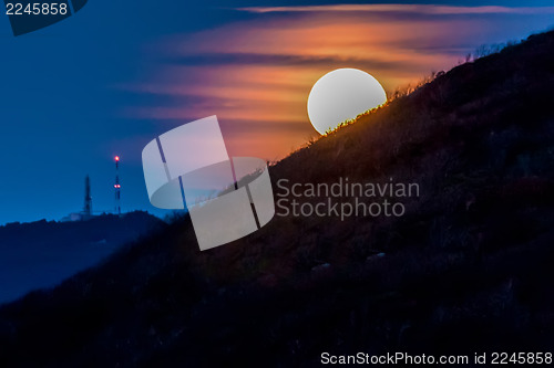 Image of Moon shining bright behind black mountains