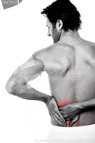 Image of Young man holding his lower back in pain