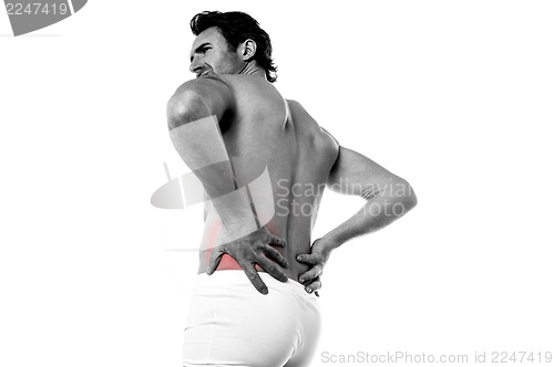 Image of Young man holding his lower back in pain