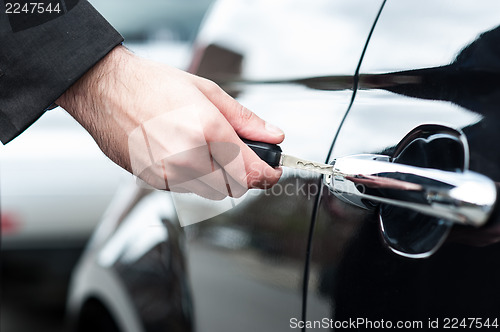 Image of Man inserting car key into the door lock