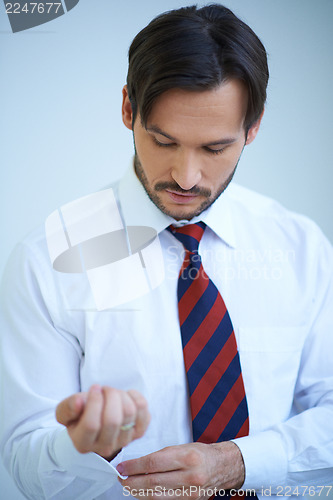 Image of Attractive young man doing up his shirt cuffs