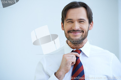 Image of Happy bearded man straightening his tie