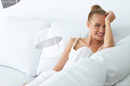 Image of Happy woman sitting on couch in her home