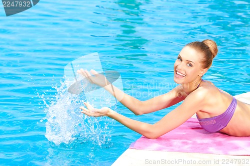 Image of Happy woman splashing water in pool