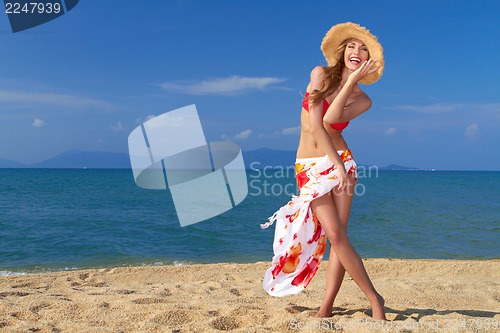 Image of Smiling woman in straw hat on sandy beach