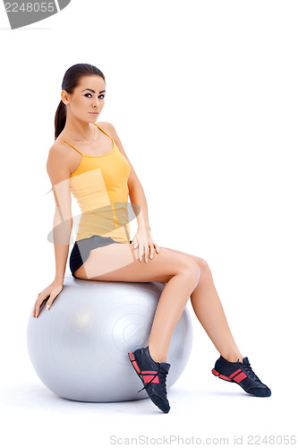 Image of Athletic woman relaxing on fitness ball