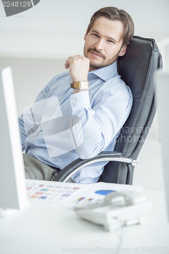 Image of Handsome businessman sitting in chair in front of computer