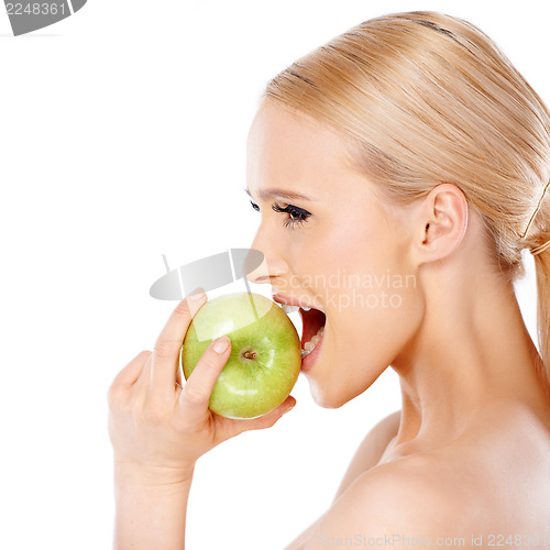 Image of Side view of blond woman  she bites an apple